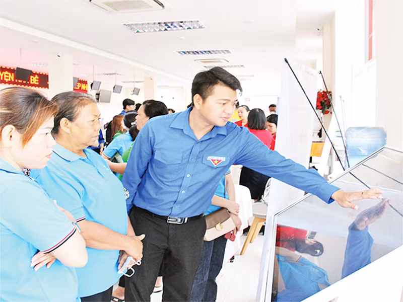 Đoàn viên, thanh niên hướng dẫn người dân thực hiện giao dịch hành chính qua nền tảng công nghệ tại UBND huyện Nhà Bè. (Ảnh THẾ ANH)