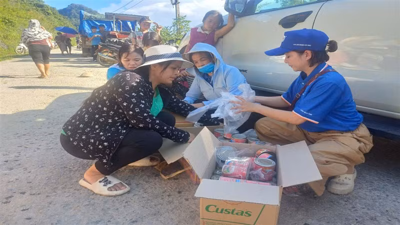 Đoàn từ thiện chia thịt hộp, cá hộp hỗ trợ người dân vùng lũ.