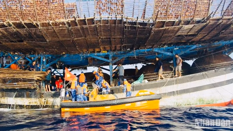 Lực lượng cứu nạn tàu Cảnh sát biển 8002 tiếp cận ngư dân tàu QNa 90129 trên tàu câu mực để chăm sóc y tế.