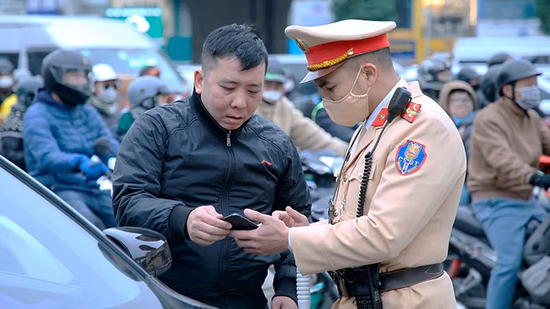 Cán bộ Cảnh sát giao thông, Công an thành phố Hà Nội trao đổi, hướng dẫn người dân tuân thủ pháp luật khi tham gia giao thông. (Ảnh: NAM PHONG)