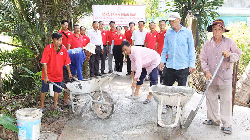 Thành viên Hội Chữ thập đỏ xã Đông Thạnh, thị xã Bình Minh (tỉnh Vĩnh Long) tham gia vá đường giao thông nông thôn. (Ảnh: BÁ DŨNG)