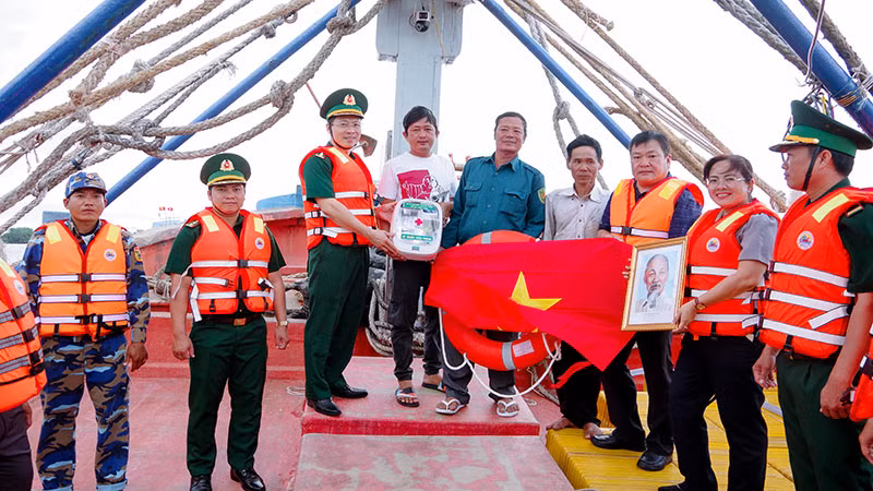 Tuần tra kiểm soát kết hợp tặng tủ thuốc Biên phòng, ảnh Bác Hồ, cờ Tổ quốc và phao cứu sinh cho chủ tàu cá.