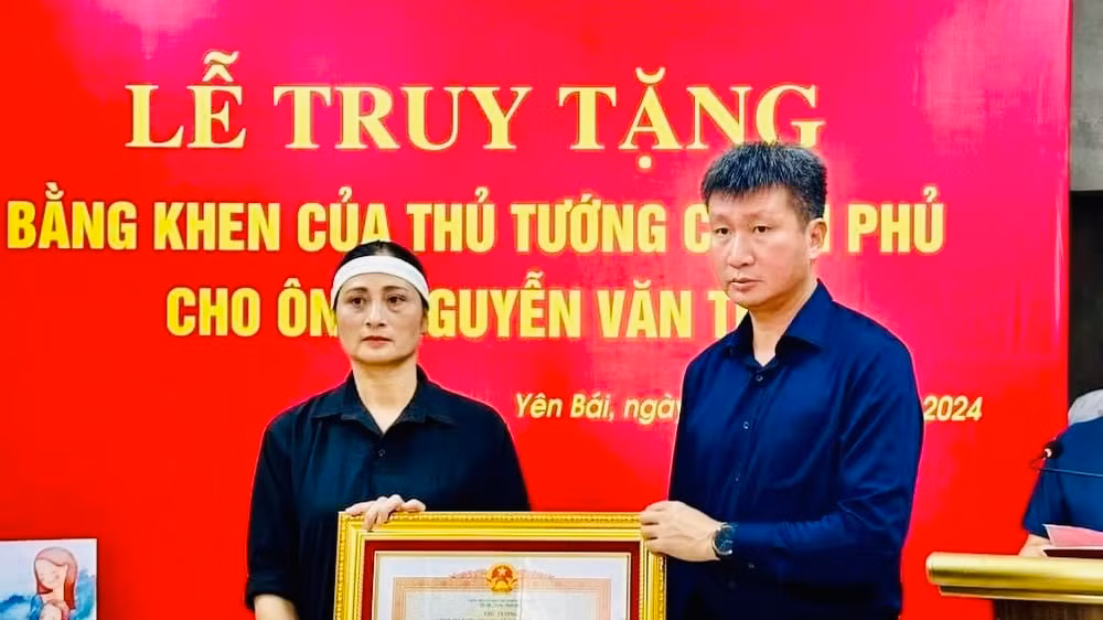 Chủ tịch Ủy ban nhân dân tỉnh Yên Bái Trần Huy Tuấn trao Bằng khen của Thủ tướng Chính phủ cho gia đình anh Nguyễn Văn Thi. (Ảnh: THANH SƠN)