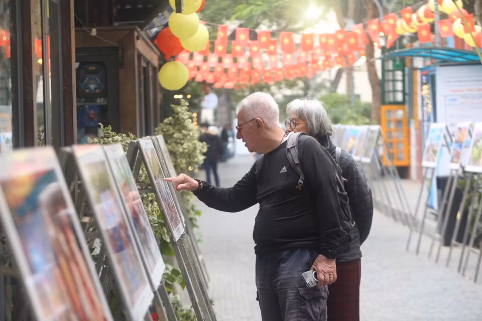 Du khách nước ngoài xem trưng bày ảnh với chủ đề “Hà Nội vươn mình bứt phá” do Báo Kinh tế & Đô thị tổ chức tại Phố Sách Hà Nội.