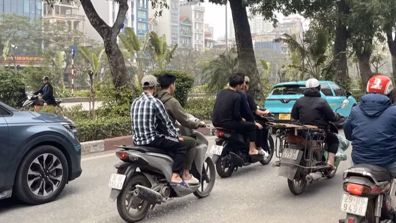 Xe máy "kẹp ba" và không đội mũ bảo hiểm - ghi nhận tại đường Láng, quận Đống Đa.