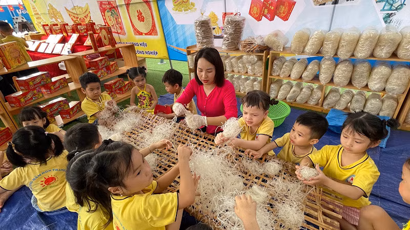 Cô giáo mầm non hướng dẫn trẻ kỹ năng cuộn bánh đa gạo.