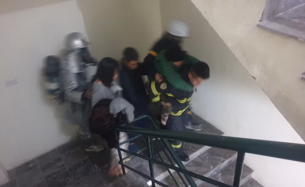 Cảnh sát phòng cháy, chữa cháy cõng cụ già thoát khỏi vụ hỏa hoạn theo cầu thang bộ. (Ảnh: Công an cung cấp)