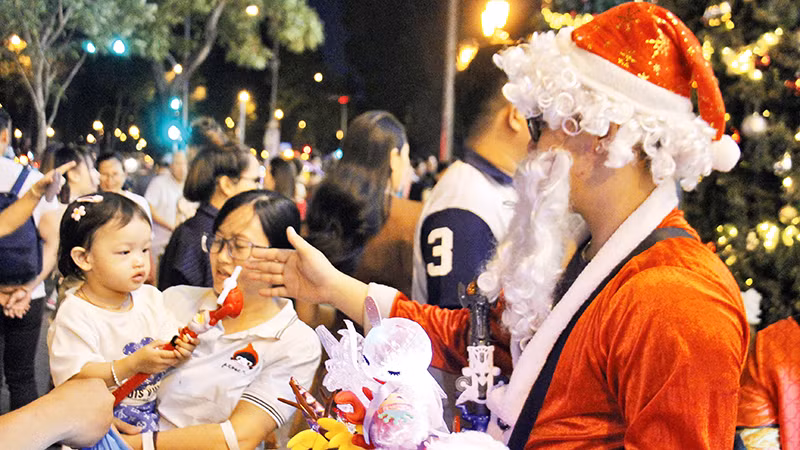 Ông già Noel phát quà cho các trẻ em tại khu vực trang trí giáng sinh tại trung tâm thành phố (Ảnh THẾ ANH)