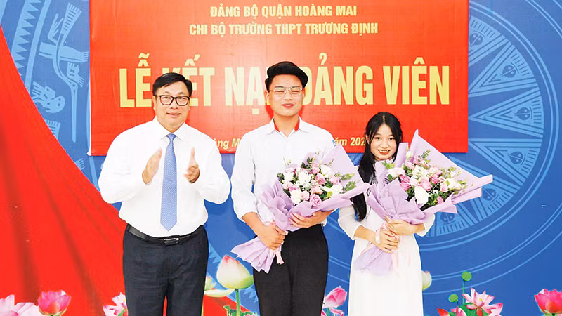 Đồng chí Nguyễn Quang Hiếu, Bí thư Quận ủy, Chủ tịch HĐND quận Hoàng Mai tặng hoa chúc mừng hai học sinh Trường THPT Trương Định được kết nạp vào đảng.