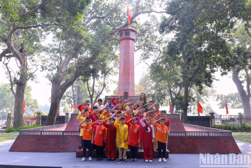 Cô và trò trường Tiểu học Tràng An (quận Hoàn Kiếm) thực hiện nghi thức chào cờ tại triển lãm tương tác Cột cờ Hà Nội tại trụ sở Báo Nhân Dân. Ảnh: Thế Đại
