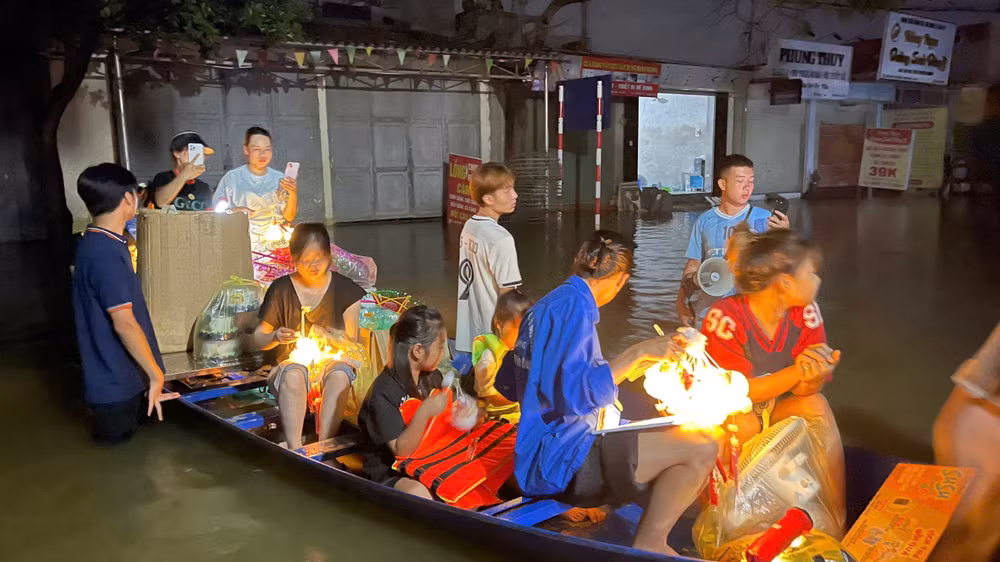 Đúng 7 giờ tối, những chiếc thuyền nhỏ được cả nhóm... đẩy ra con đường liên thôn vẫn ngập sâu trong nước lụt. Phía trên, hàng chục chiếc đèn đã được thắp, tỏa sáng lung linh.