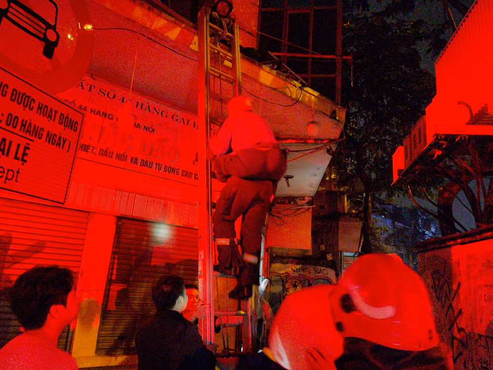 Các chiến sĩ cõng một cụ già xuống đất an toàn.