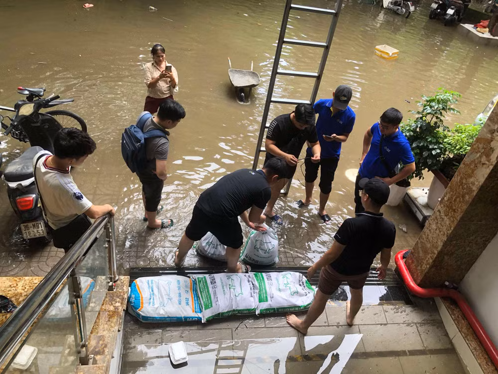 Nước từ bên ngoài đường dâng cao tràn vào cửa hầm. Để hạn chế tình trạng trên, những người sống tại chung cư mini đã phải dùng cát đựng trong các bao tải để chặn lại trước cửa.