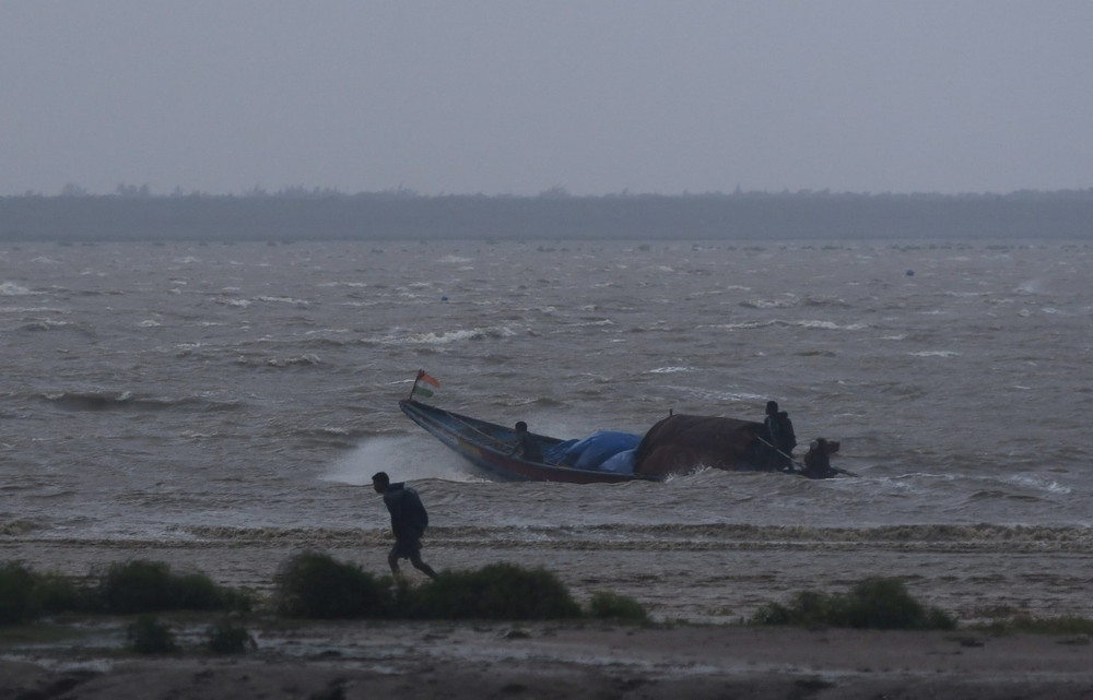 Một ngư dân ở Bhadrak (bang Odisha, Ấn Độ) cố gắng đưa thuyền vào nơi neo đậu khi bão Dana đang tới gần. (Ảnh: Reuters)