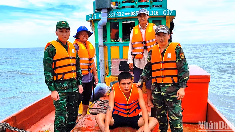 Nạn nhân Minh (ngồi) bị trôi dạt trên biển được Bộ đội Biên phòng Cà Mau cứu vớt đưa vào bờ an toàn. 