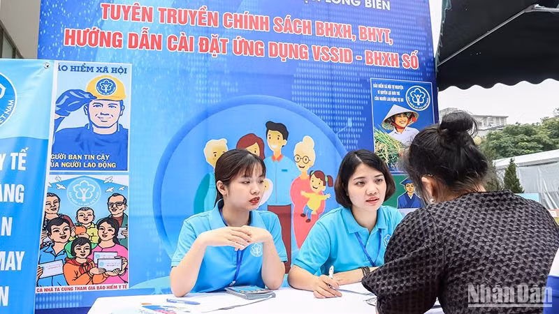 Cán bộ Bảo hiểm xã hội quận Long Biên, Hà Nội giới thiệu về chính sách bảo hiểm xã hội, bảo hiểm y tế với người dân. (Ảnh NGÂN ANH)
