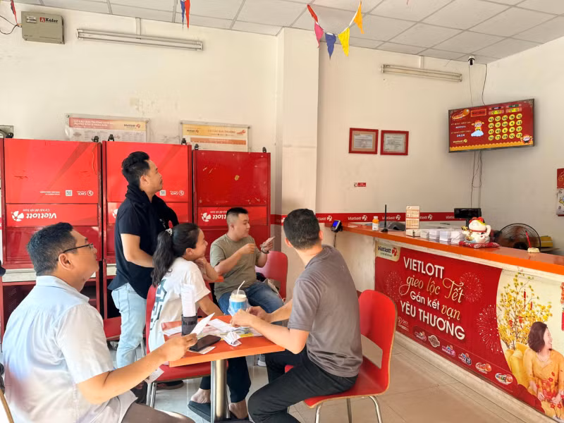 Bên trong một điểm bán vé số Vietlott có đông đảo người chơi theo dõi kết quả mở thưởng Keno trực tiếp trên màn hình.