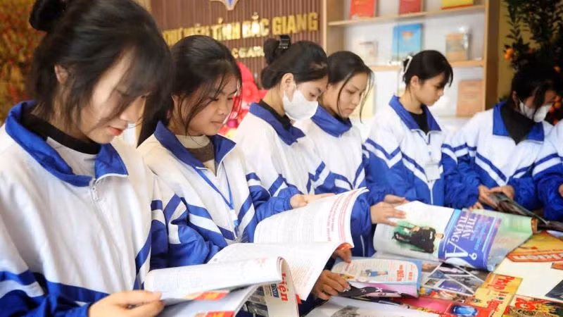 Các em học sinh đọc sách tại gian trưng bày chào mừng 50 năm Ngày Giải phóng miền nam, thống nhất đất nước tại Thư viện Bắc Giang.
