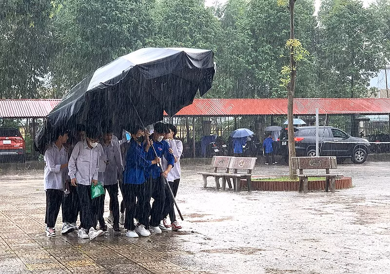 Chiến sĩ tình nguyện "Hoa phượng đỏ" che mưa cho các thí sinh ở kỳ thi tốt nghiệp trung học phổ thông vừa qua.