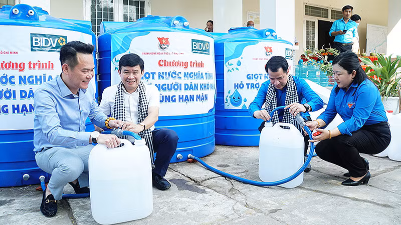 Các đồng chí đại diện Trung ương Đoàn, Hội Doanh nhân trẻ Việt Nam và các đơn vị liên quan lấy nước sạch vào can để trao tặng người dân địa phương.