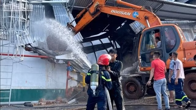 Các lực lượng chức năng phá hàng rào tôn để dập lửa.