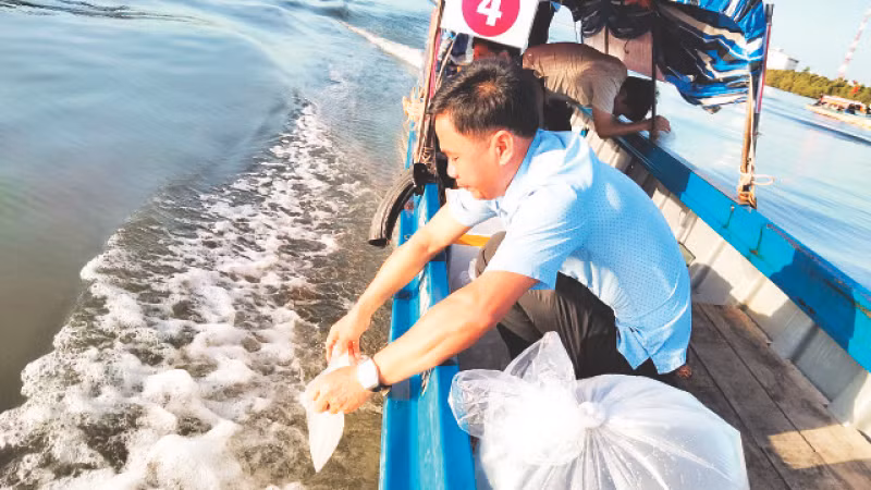 Người dân thành phố Hà Tiên thả cá, tôm, cua giống xuống đầm Đông Hồ. 