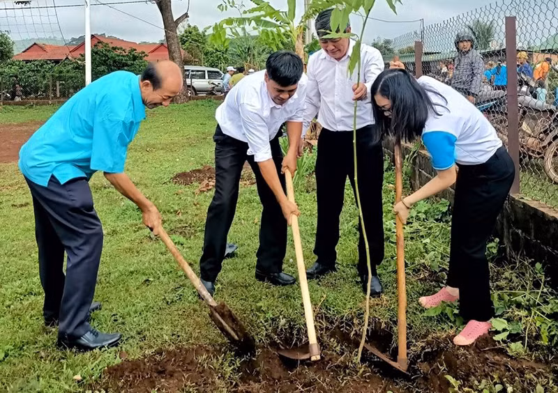 Các đại biểu tham gia trồng cây trong khuôn viên nhà rông làng Kép 1.