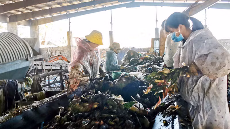 Công nhân phân loại rác trên dây chuyền xử lý rác thải.