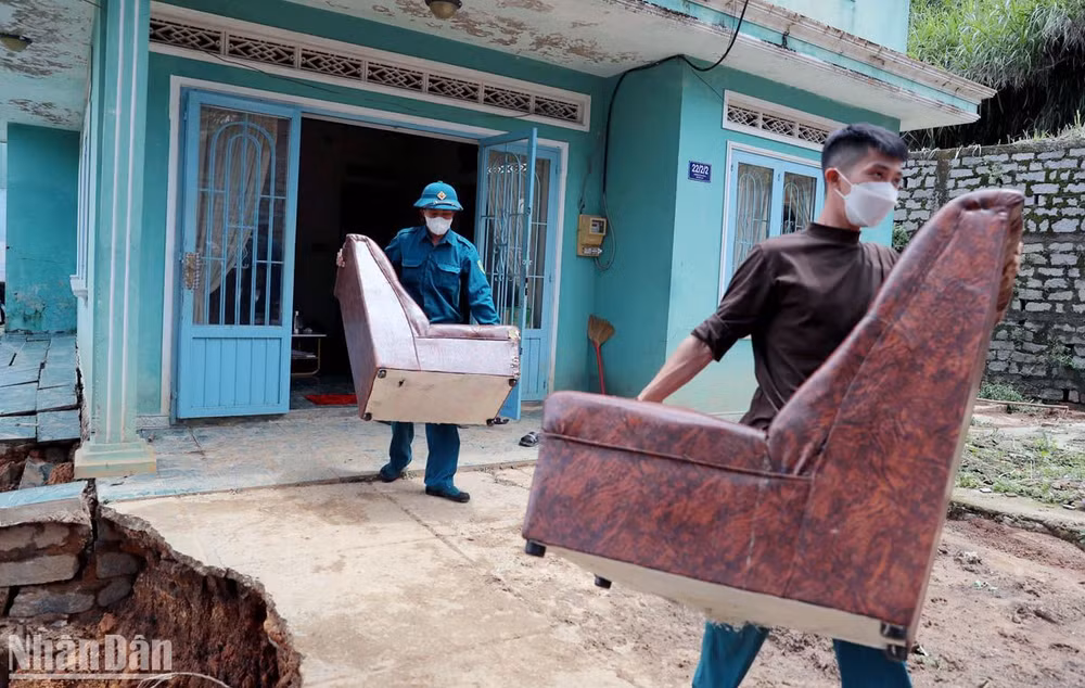 Lực lượng chức năng hỗ trợ người dân di dời đồ đạc ra khỏi khu vực sạt lở. 