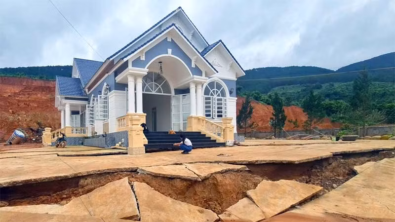 Sân trước ngôi nhà của ông Thắng bị nứt toác, phía sau nhà bị đất sạt trượt.