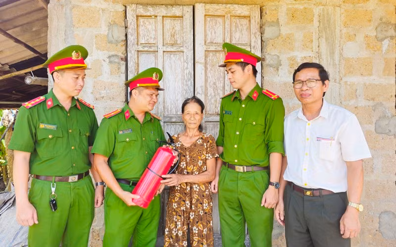 Công an xã chính quy xã Triệu Giang, huyện Triệu Phong tặng bình chữa cháy cho bà Hồ Thị Thúy, hộ nghèo của địa phương.