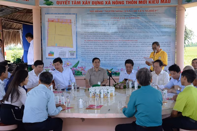 Thủ tướng Phạm Minh Chính nghe lãnh đạo Hợp tác xã Dịch vụ nông nghiệp Thắng Lợi giới thiệu về cánh đồng lúa canh tác theo mô hình công nghệ cao.