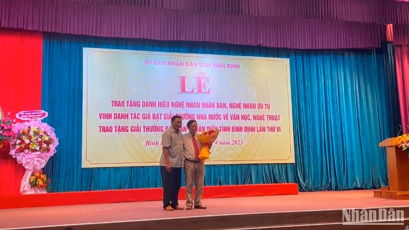 Phó Bí thư Tỉnh ủy Bình Định Lê Kim Toàn (trái) tặng hoa chúc mừng nhà thơ, nhà viết kịch Văn Trọng Hùng vinh dự được trao tặng Giải thưởng Nhà nước về văn học nghệ thuật.