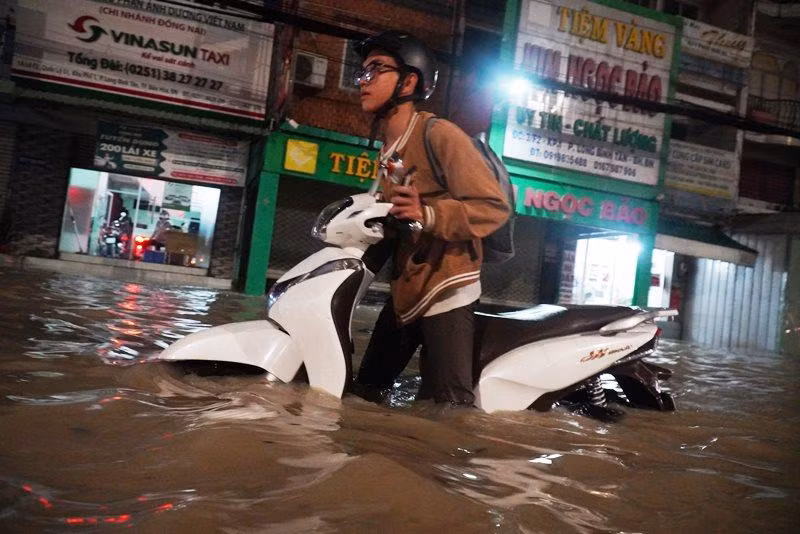 Người điều khiển xe mô-tô vượt qua dòng nước ngập.