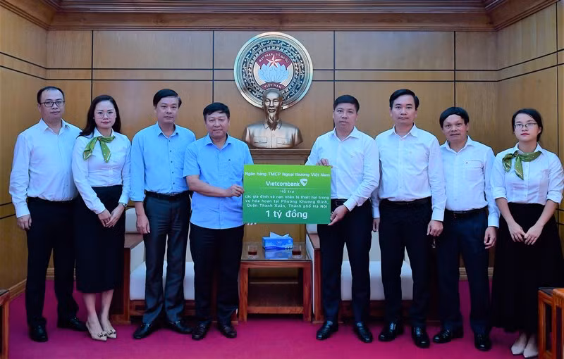Đồng chí Hồng Quang - Thành viên HĐQT kiêm Giám đốc Khối Nhân sự, Chủ tịch Công đoàn Vietcombank (thứ 4 từ phải sang) trao cho đồng chí Phạm Anh Tuấn - Phó Chủ tịch Ủy ban Mặt trận Tổ quốc Việt Nam thành phố Hà Nội (thứ 4 từ trái sang) biển tượng trưng số tiền 1 tỷ đồng hỗ trợ các gia đình và nạn nhân bị thiệt hại trong vụ hỏa hoạn tại quận Thanh Xuân, Hà Nội.
