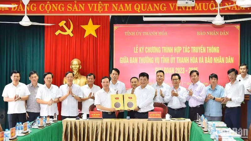 Phó Tổng Biên tập Báo Nhân Dân Quế Đình Nguyên và Phó Bí thư Thường trực Tỉnh ủy Thanh Hóa Lại Thế Nguyên trao nhau bản thỏa thuận hợp tác truyền thông giữa 2 cơ quan trước sự chứng kiến của lãnh đạo 2 đơn vị. (Ảnh: Thủy Nguyên)