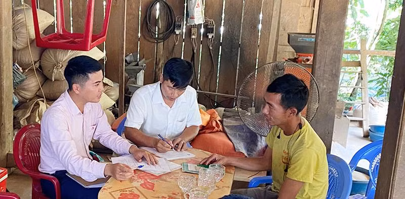 Cán bộ tín dụng Ngân hàng Chính sách xã hội huyện Mường Nhé hỗ trợ người dân bản Cây Sặt, xã Huổi Lếch làm thủ tục vay vốn phát triển chăn nuôi.