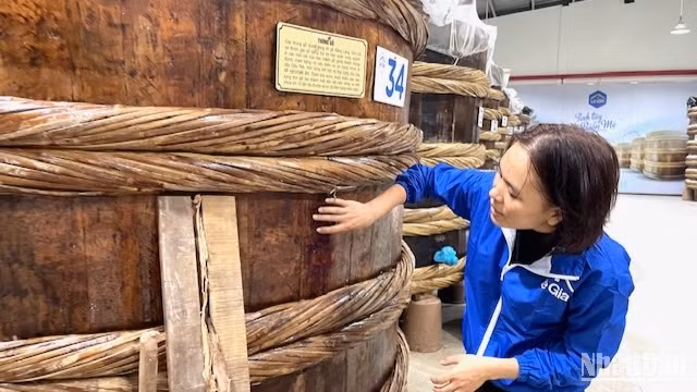 Nhân viên xưởng sản xuất nước mắm Lê Gia giới thiệu về thùng ủ mắm từ gỗ bời lời.