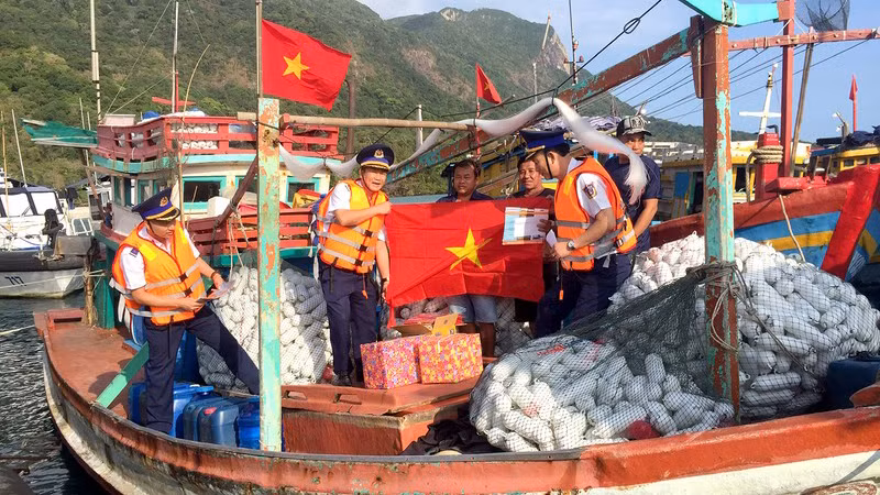Cán bộ Bộ Tư lệnh Cảnh sát biển trao cờ Tổ quốc và quà tặng ngư dân tại cảng Bến Đầm, huyện Côn đảo, tỉnh Bà Rịa-Vũng Tàu. (Ảnh: nhandan.vn) 