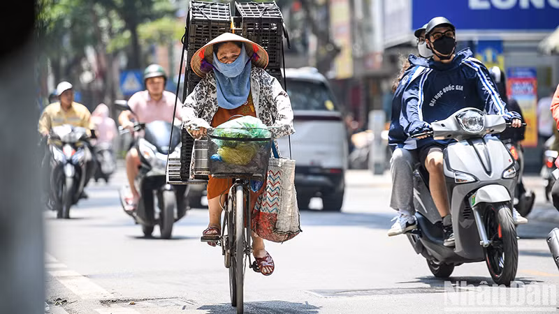 Dưới ánh nắng gay gắt, kèm nhiệt độ cao, nhiều người lao động ở Hà Nội phải trùm kín người khi di chuyển ngoài trời. Ảnh: THÀNH ĐẠT
