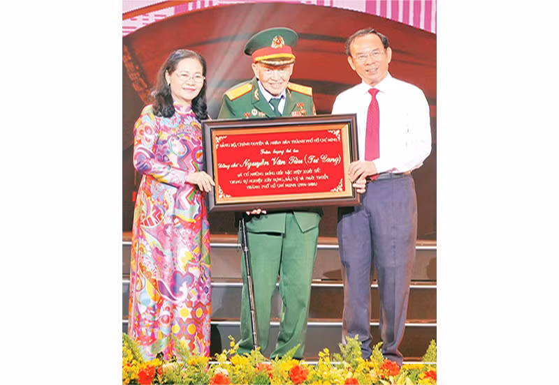 Đồng chí Nguyễn Văn Nên, Ủy viên Bộ Chính trị; Bí thư Thành ủy Thành phố Hồ Chí Minh trao bảng tôn vinh Đại tá, Anh hùng Lực lượng Vũ trang nhân dân Nguyễn Văn Tàu (Tư Cang).