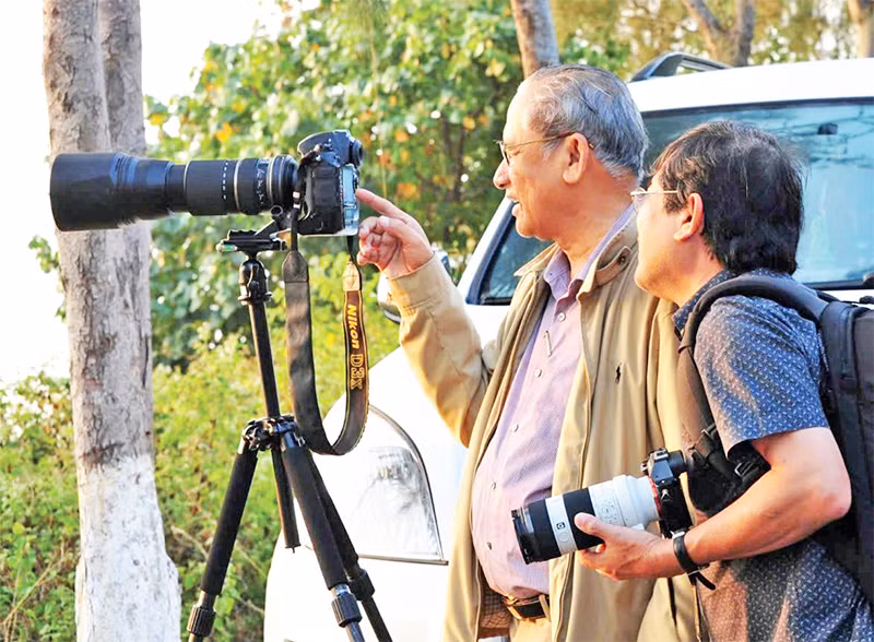 Nghệ sĩ nhiếp ảnh Trần Lam (bên trái) chia sẻ kinh nghiệm với các nghệ sĩ nhiếp ảnh cùng đi sáng tác ảnh. (Ảnh KIM ANH) 