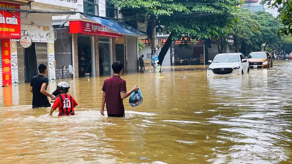 Người dân chạy lũ tại đường Thành Công, phường Nguyễn Thái Học, thành phố Yên Bái. (Ảnh: THANH SƠN)