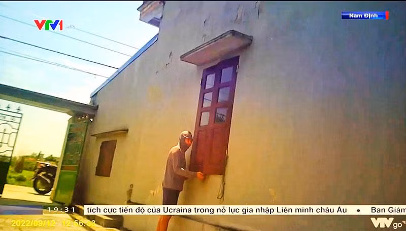 Người mua ma túy đưa tiền qua khe cửa sổ bên hông ngôi nhà. (Ảnh từ clip phóng sự của VTV)