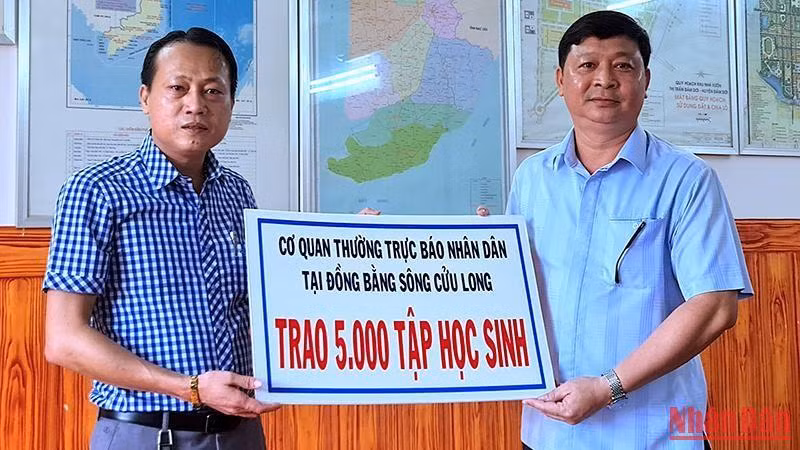 Chủ tịch Ủy ban nhân dân huyện Đầm Dơi (bìa phải) tiếp nhận 5.000 tập hỗ trợ từ Cơ quan Thường trực Báo Nhân Dân tại vùng đồng bằng sông Cửu Long.