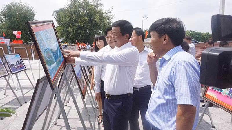 Các đại biểu và nhân dân tham quan gian trưng bày ảnh và tranh tuyên truyền cổ động.