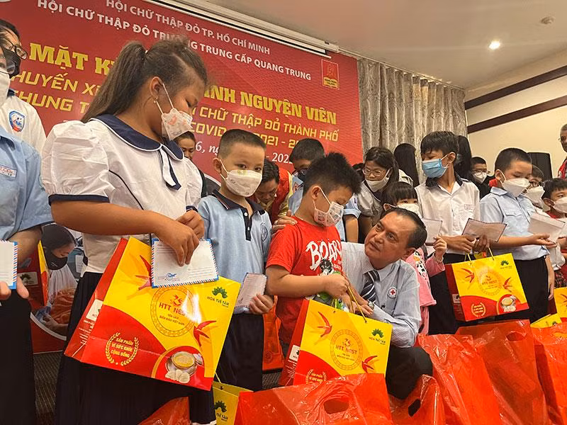 Chủ tịch Hội Chữ thập đỏ Thành phố Hồ Chí Minh Trần Trường Sơn (người ngồi) tặng quà cho các bé.