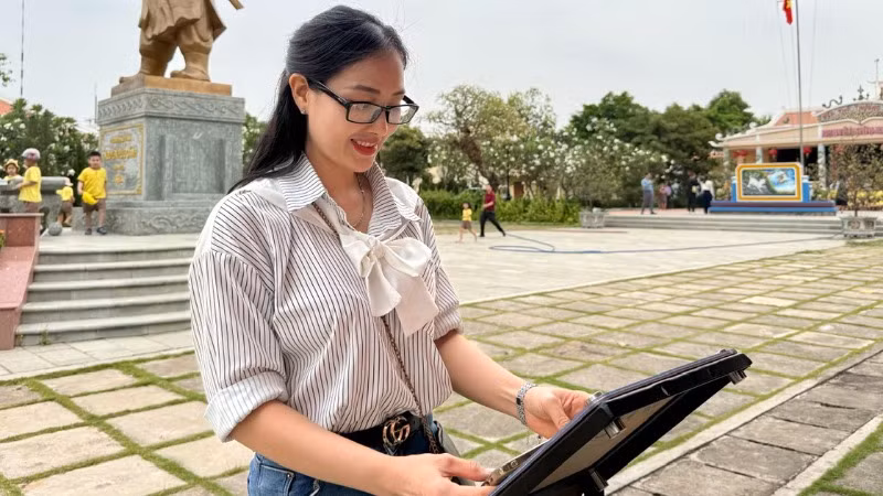 Cô giáo Trần Thị Bích Phương check-in bảng gắn chip NFC thuộc Dự án "Yêu lắm Việt Nam" của Báo Nhân Dân tại Di tích Đền thờ Nguyễn Hữu Cảnh.