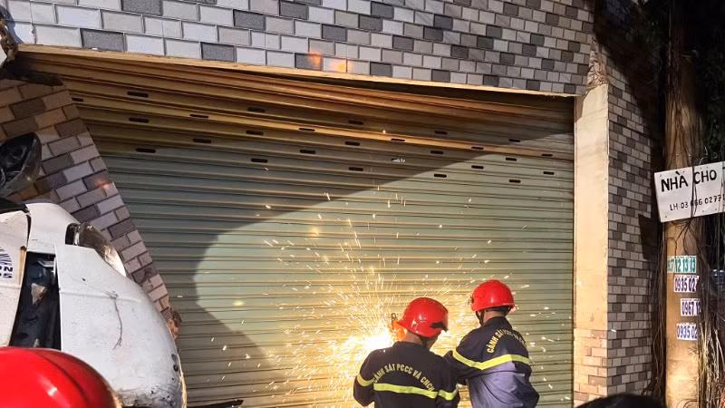 Cảnh sát tiến hành cưa cửa sắt cuốn để giải cứu nạn nhân.