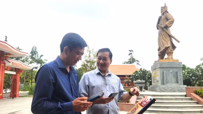 Phó Giám đốc Bảo tàng Đồng Nai Phạm Văn Minh (bên phải) giới thiệu thiết bị bảng gắn chip NFC tại Di tích Đền thờ Nguyễn Hữu Cảnh.